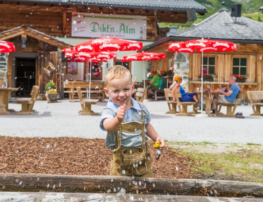 Junge spielt am Brunnen vor der Dikt'n Alm