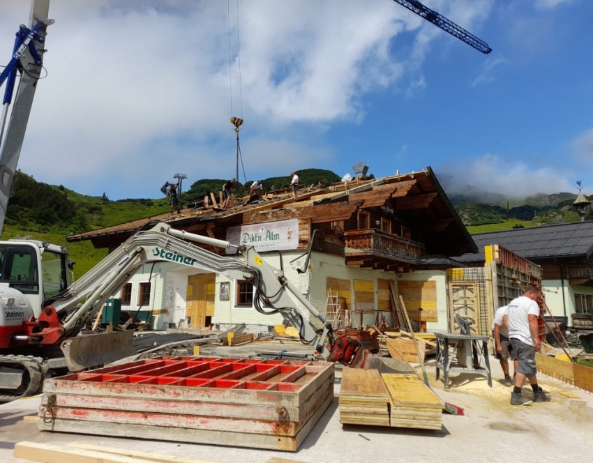 Handwerker und Maschinen im Einsatz während der Umbauarbeiten der Alm.